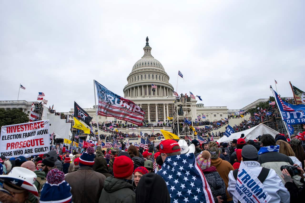 A group of Trump supporters gather outside the US Capitol waving flags and signs