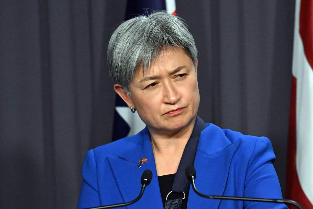Foreign Affairs Minister Penny Wong wearing a blue jacket with two small microphones in front of her.