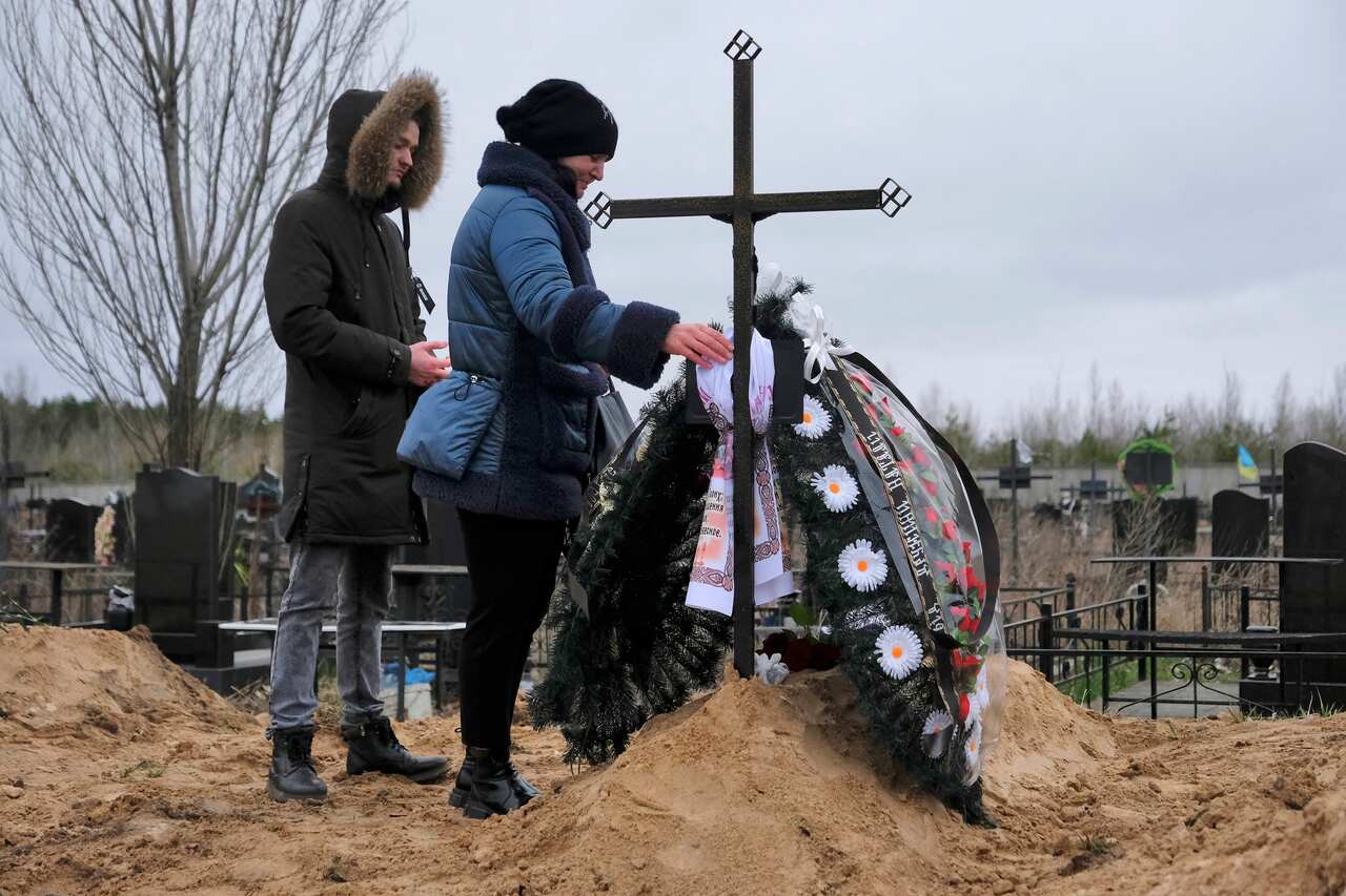 Two people standing at a grave site.