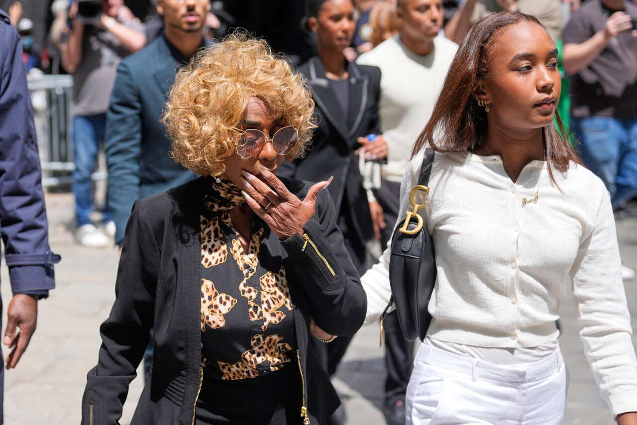 A woman in a black outfit and blonde hair walks next to a woman in a white outfit.