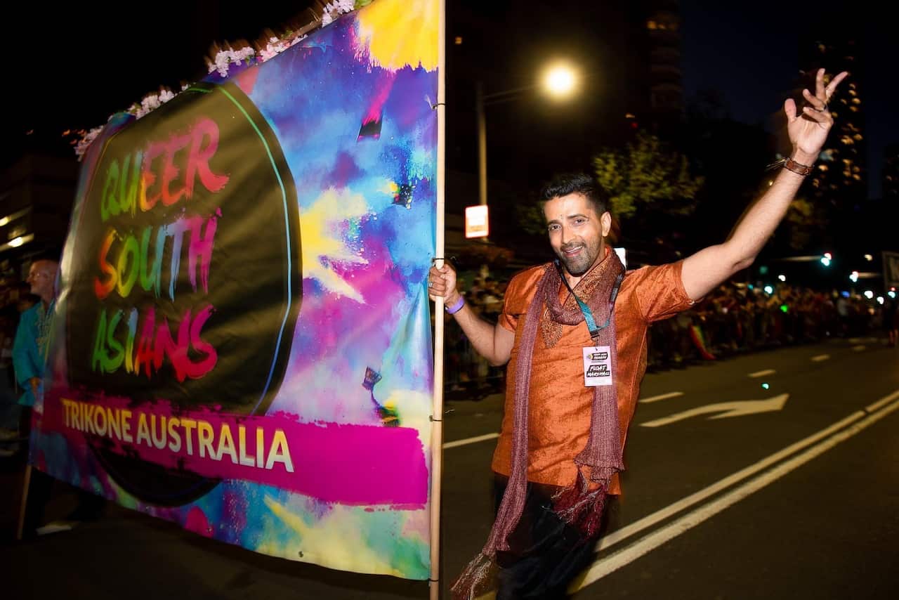 Man marching down street holding a banner that reads 'Queer South Asians'