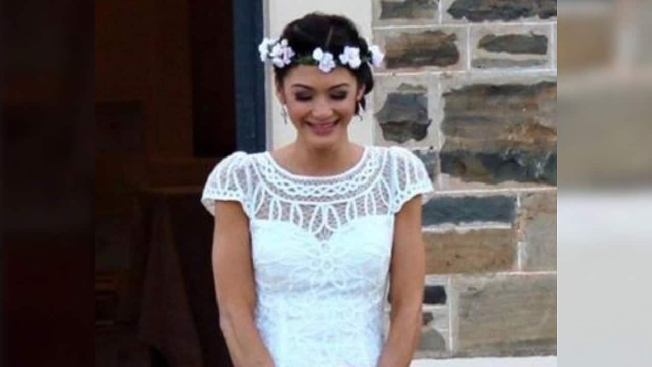 a young woman in a wedding dress in front of sandstone walls