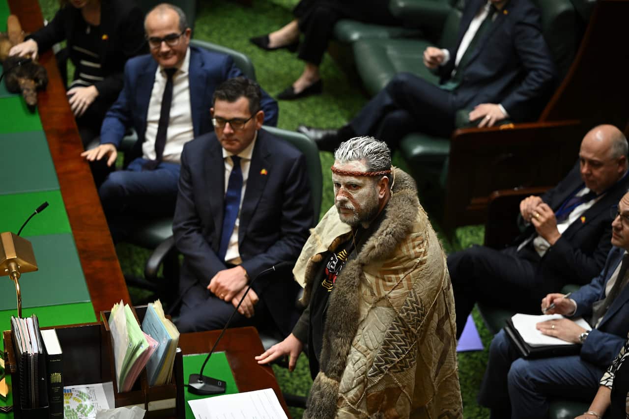 A man in traditional Indigenous clothing speaks in Victorian Parliament.