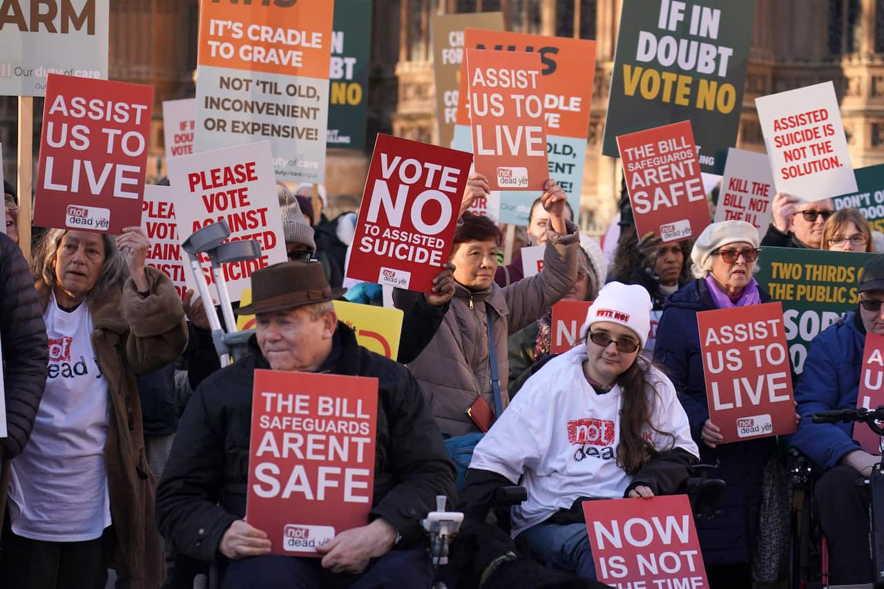 A group of people holding signs protesting against assisted dying.