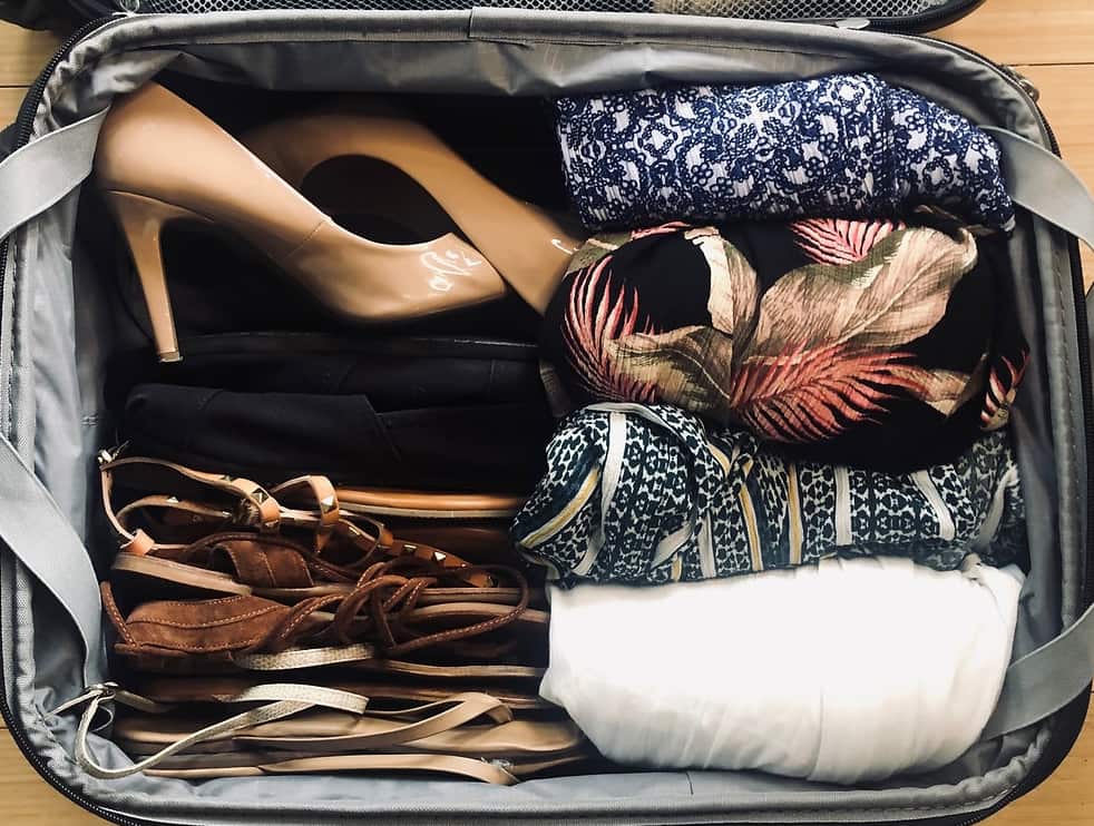 A neatly packed suitcase with clothes and shoes.