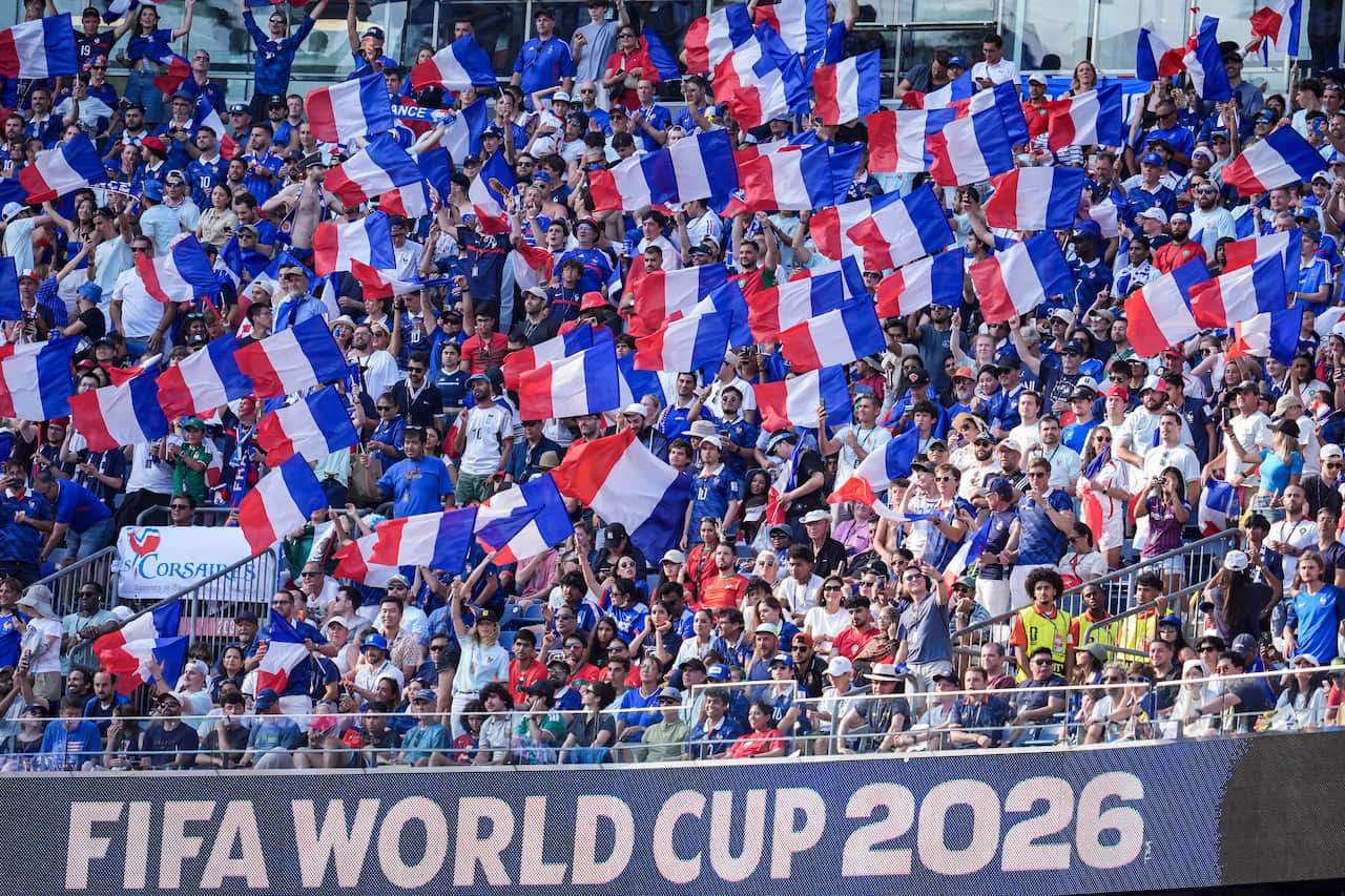 French football fans in a stadium waving French flags