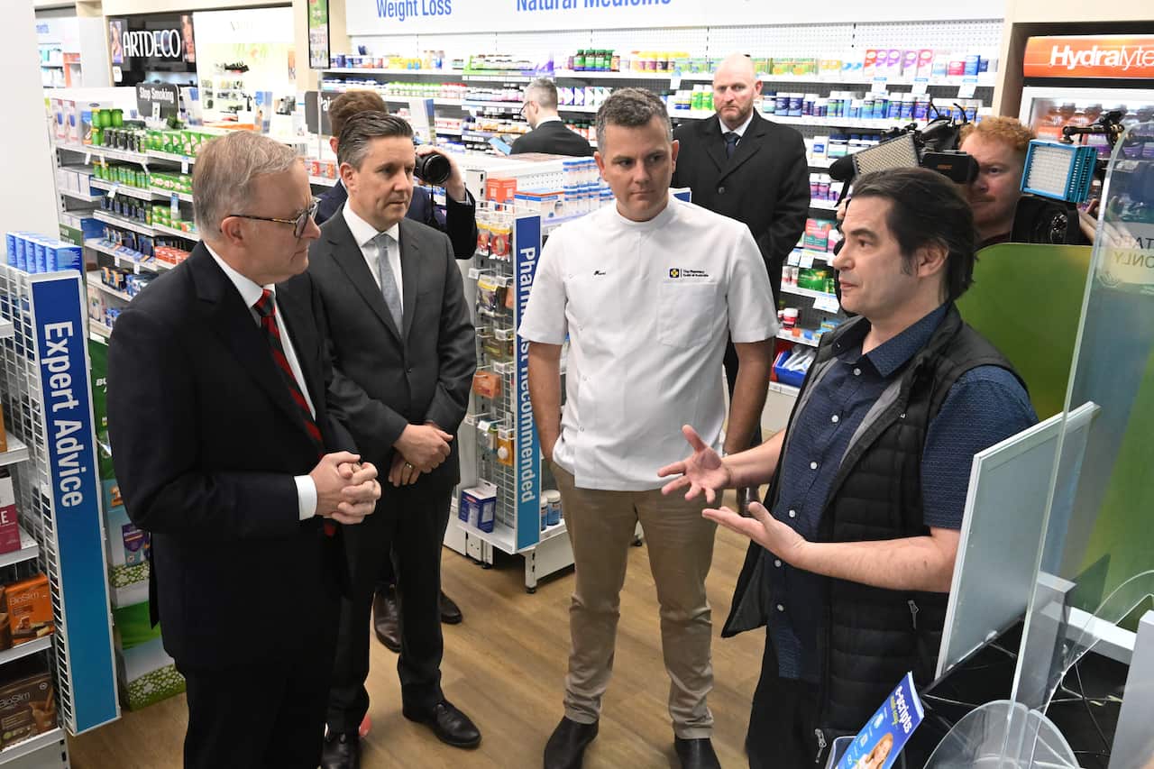 Four men talk to each other in a chemist