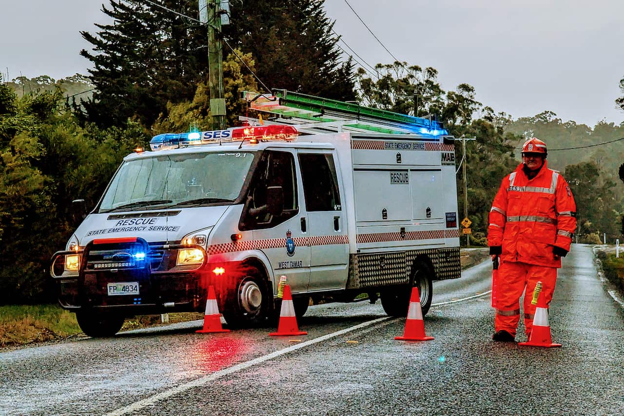 An emergency worker and vehicle standing on a road. There are traffic cones in between them.