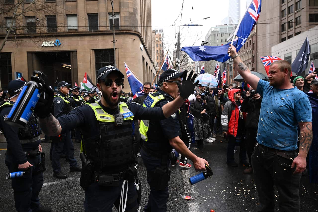 A group of protesters being held back by police officers on a street.