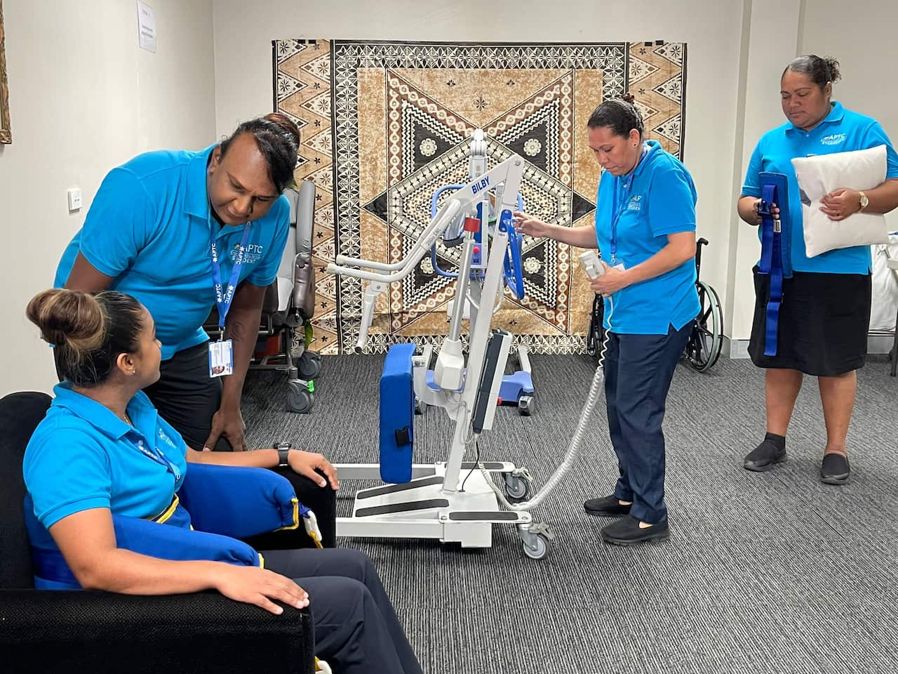 Four people in a room using nursing equipment
