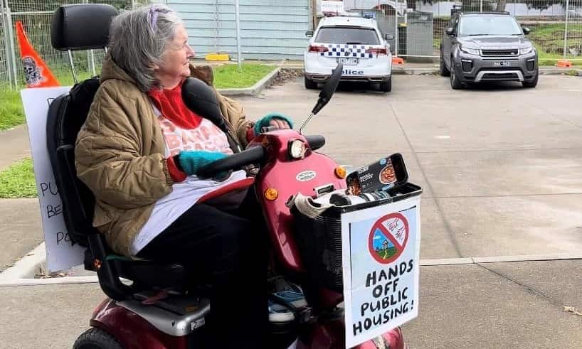 A woman on a mobility scooter with a poster saying "hands off public housing!"