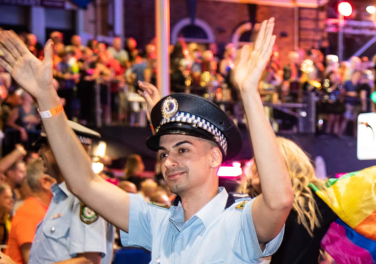 A man in police uniform waves both hands in the air