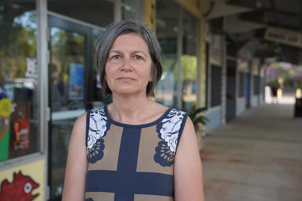 A woman looking at the camera and wearing a blue and white floral dress 