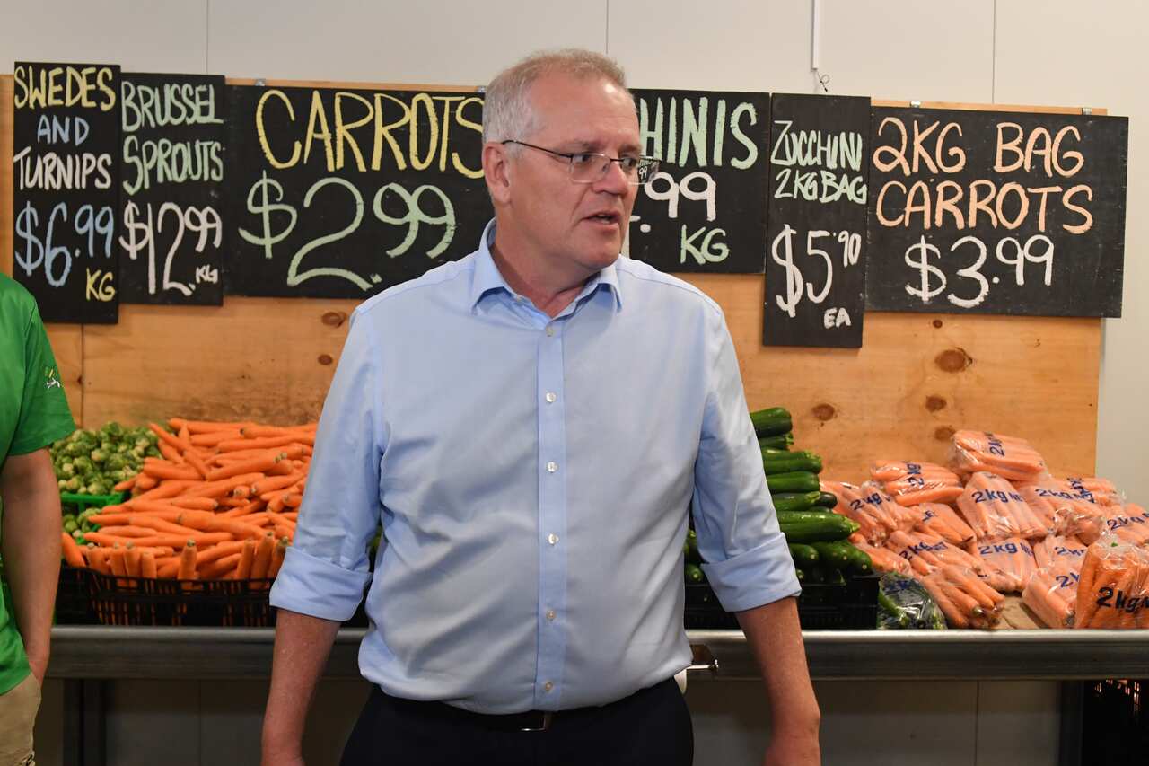 A man standing in front of a stand of vegetables.