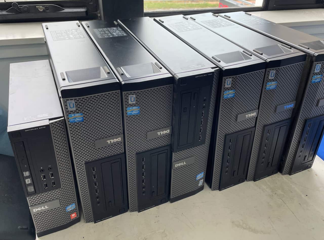 A row of computer towers on a table in front of a window.