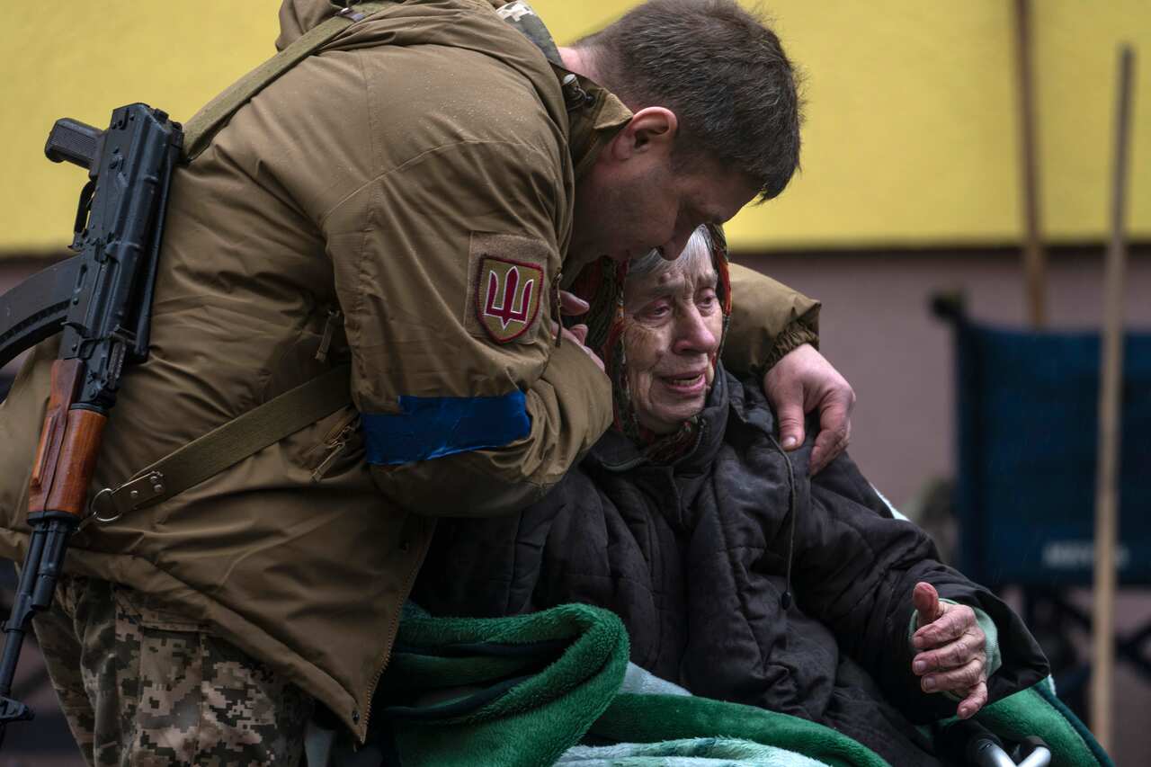 A soldier comforts an elderly woman.