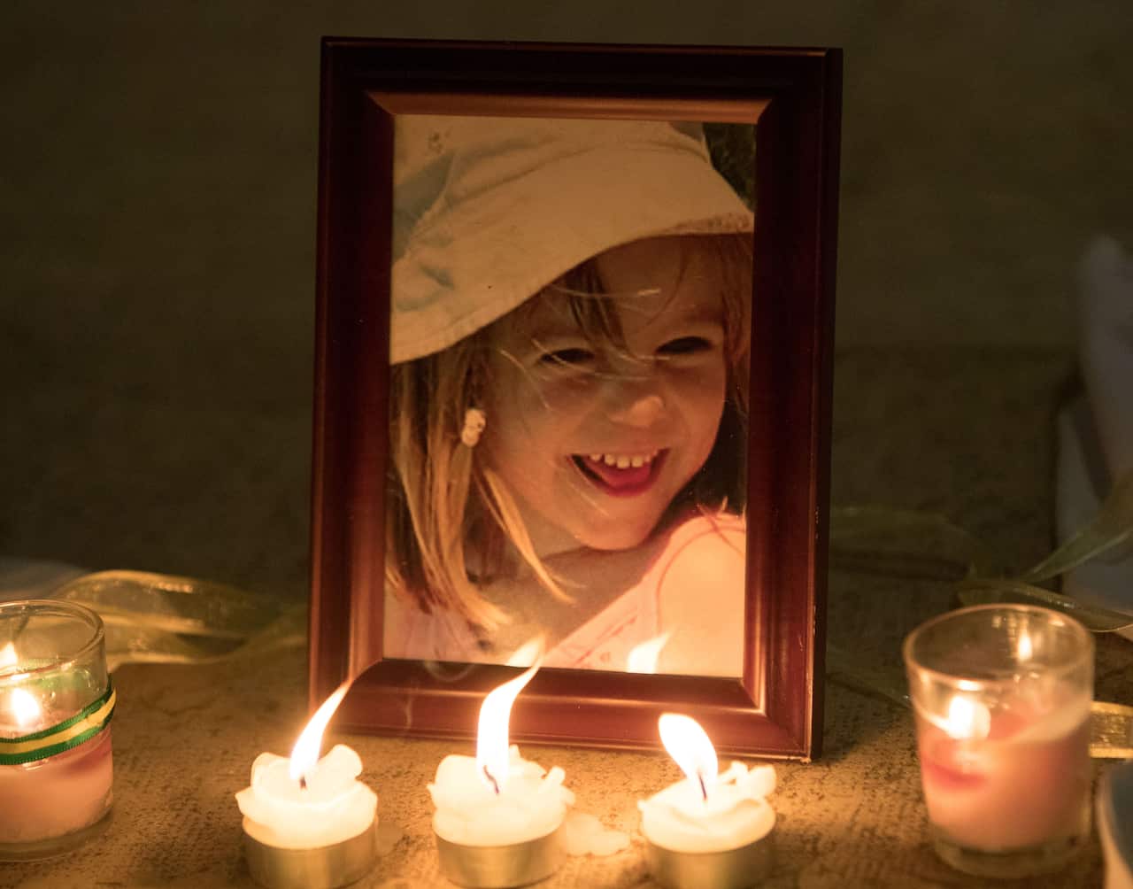 Candles in front of a photo of a young girl.