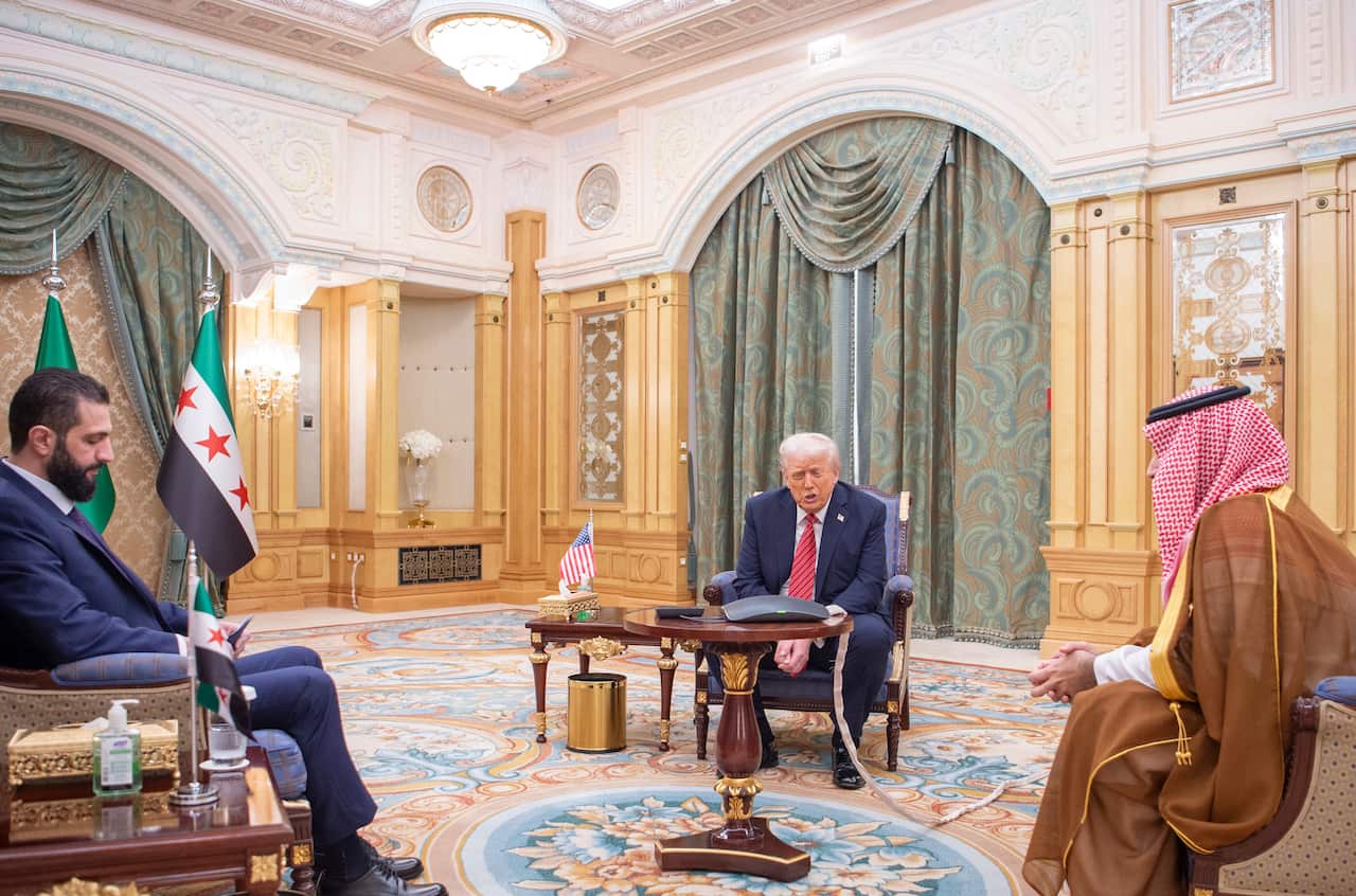 Three men sitting at different chairs in an ornate room.