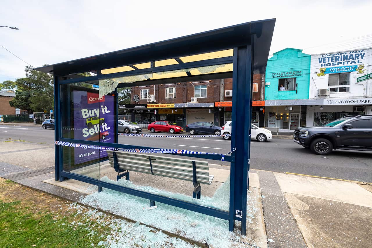 Rear view of a bus stop with shattered glass below it.