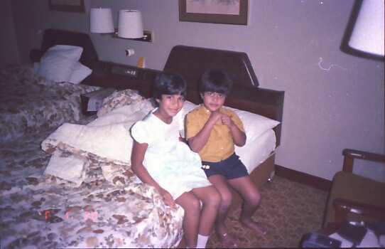 A young Pallave Dasari (8) and her little brother (5) sitting on a bed together