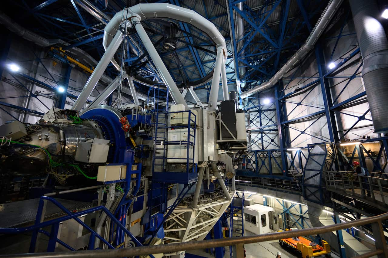 Inside a space observatory facility, a large telescope sits in the centre