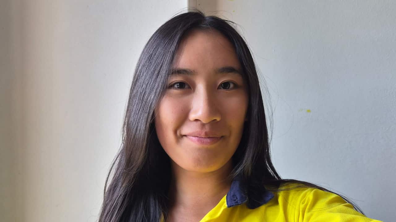 a closeup of a young woman with black hair in a high vis top