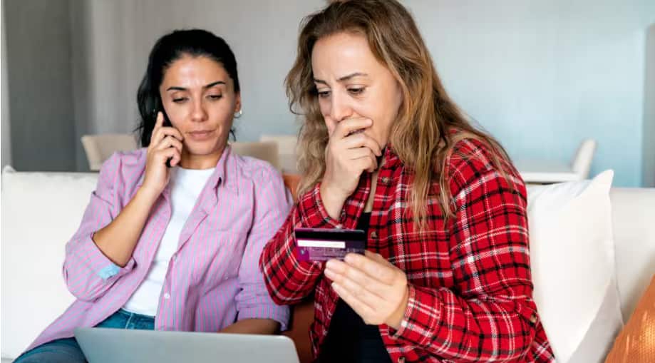 Stressed upset woman holding bank card and being surprised