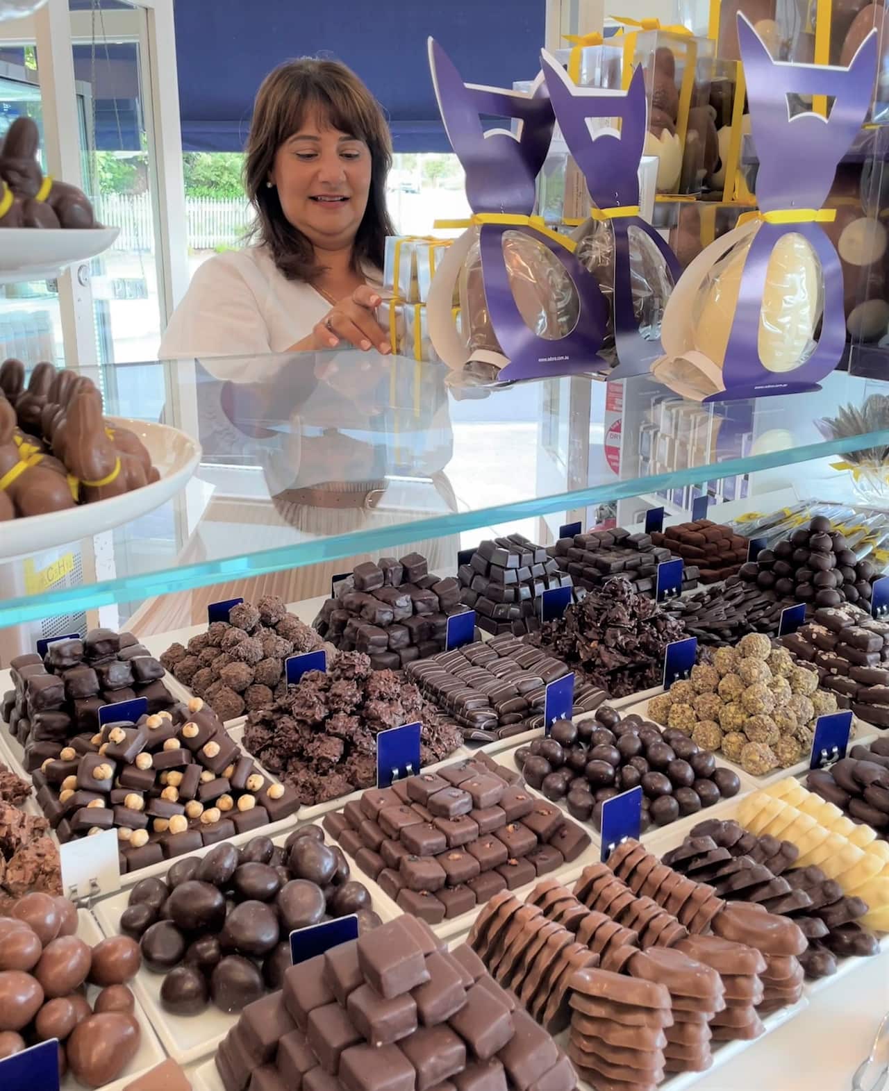 Tina Angelidis standing with an array of chocolates at the Earlwood store.