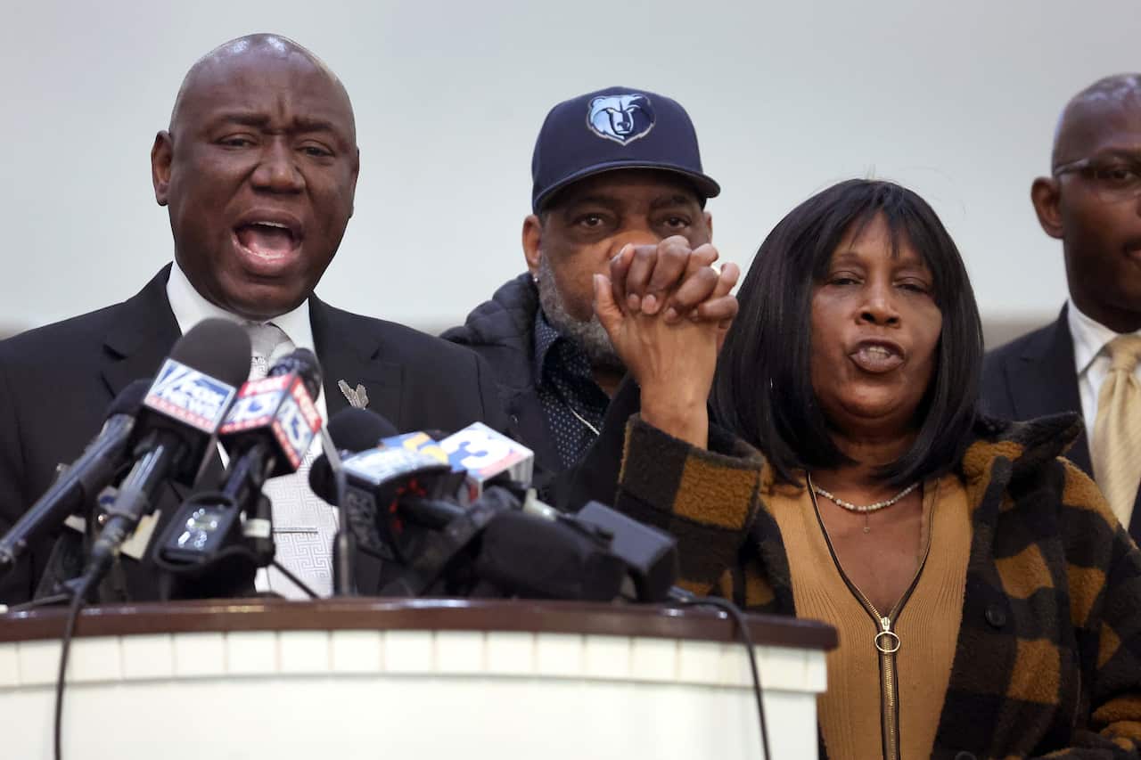 Civil rights lawyer Ben Crump stands next to RowVaughn Wells, mother of Tyre Nichols, during a press conference. They hold hands in a gesture of support.