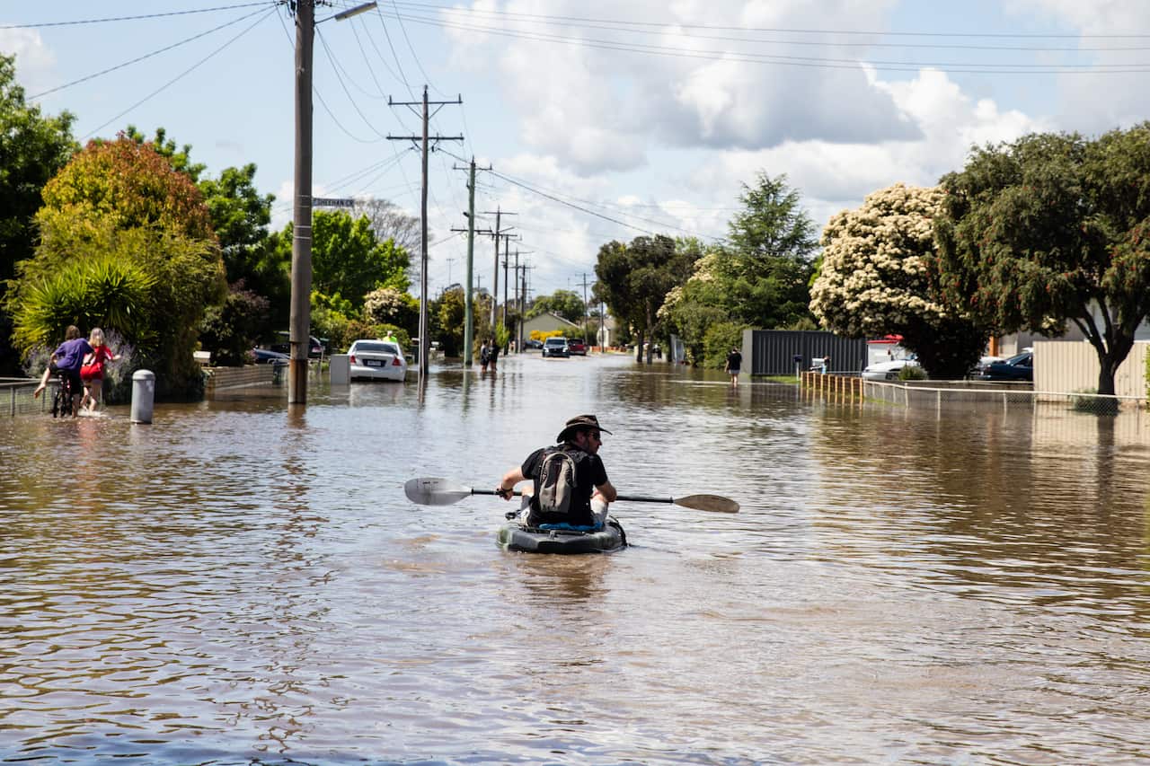 A local resident paddles through a flooded street