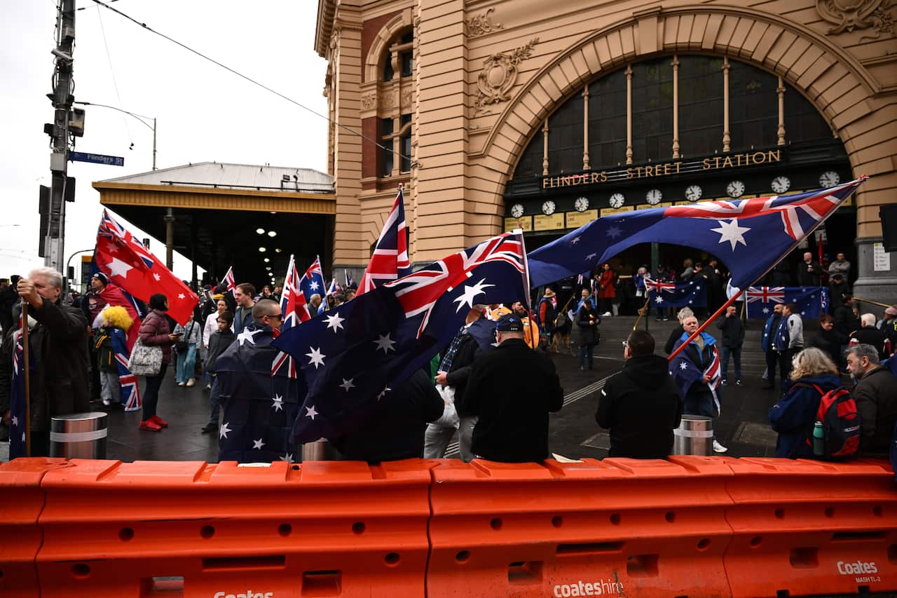A group of protesters, some waving Australian flags, outside Flinders Street Station.
