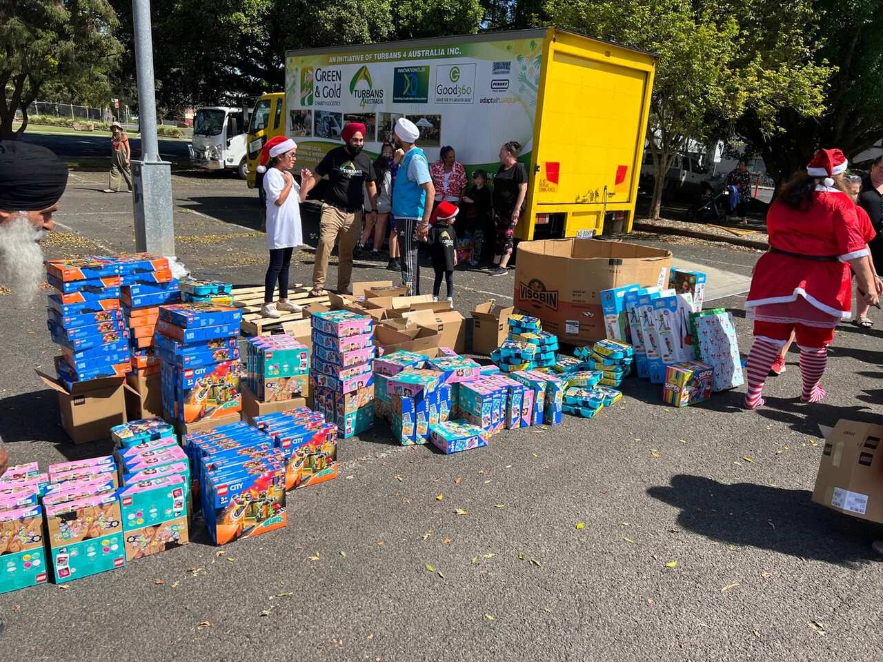 People wearing turbans and Christmas hats mill about piles of donated toys.