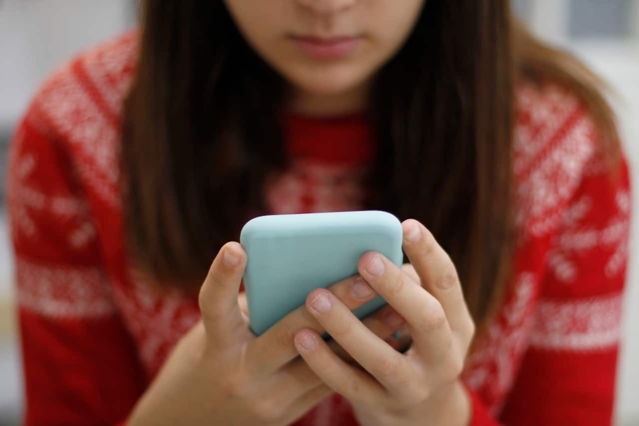 A young woman in a red shirt using a smart phone