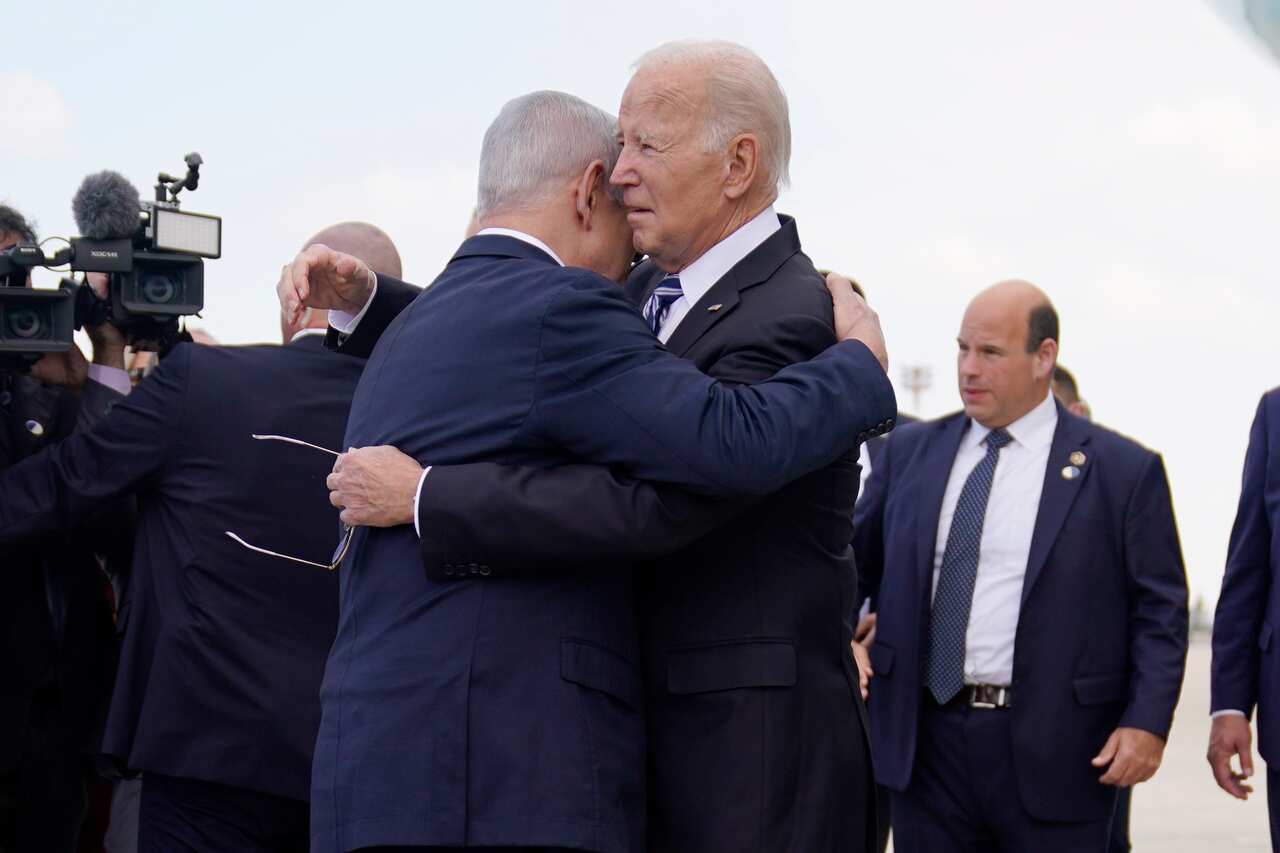 Joe Biden and Benjamin Netanyahu hug. There are other men in suits near them.