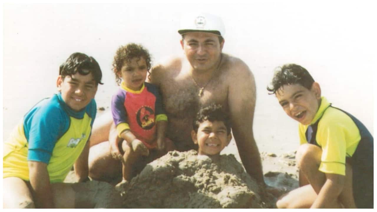 A man with his four children at the beach. 