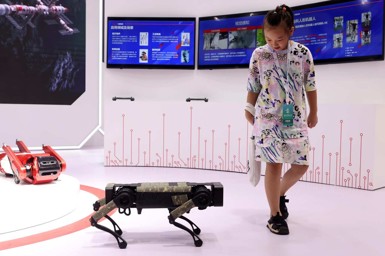 A young girl walks next to a canine-shaped robot. 
