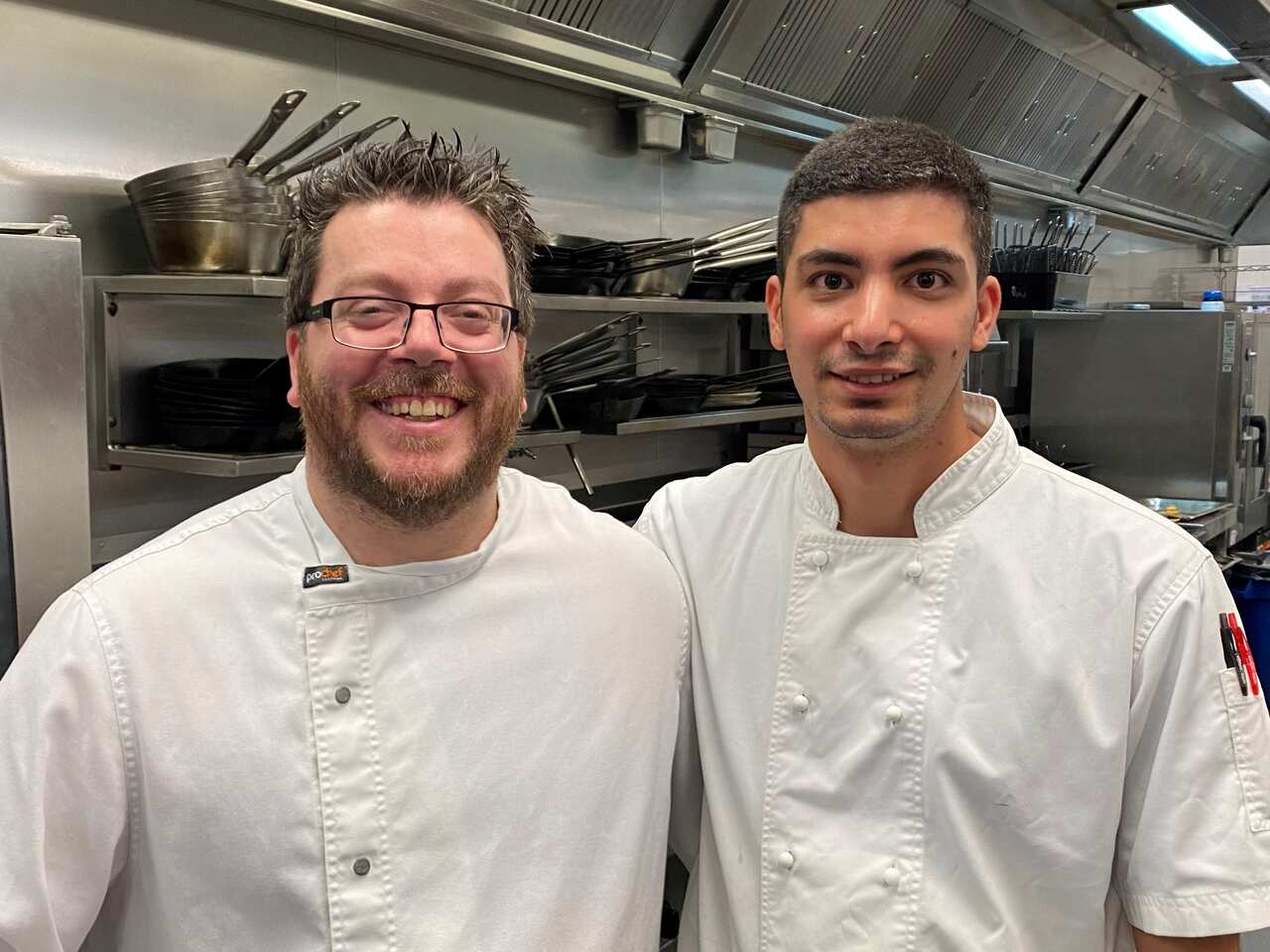 Two men in chef's clothing smiling