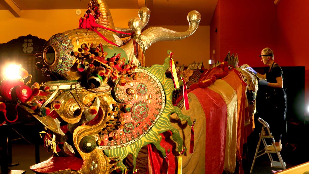 A woman stands on a stepstool as she looks at a Chinese dragon