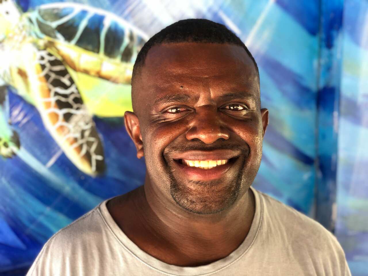 A man smiling at the camera in front of a banner with a turtle.
