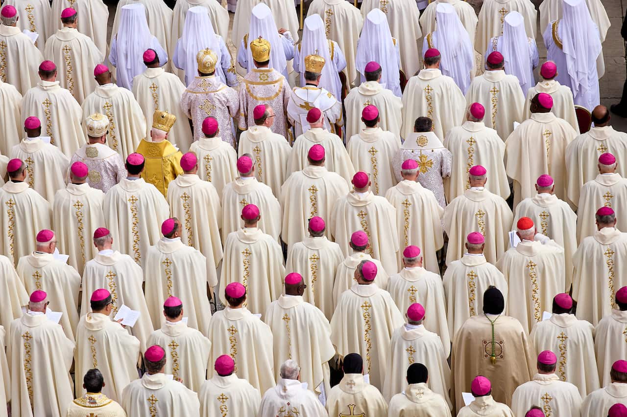 Dozens of Catholic worshippers wearing white gowns and pink caps faced forward for the inauguration of Pope Leo.