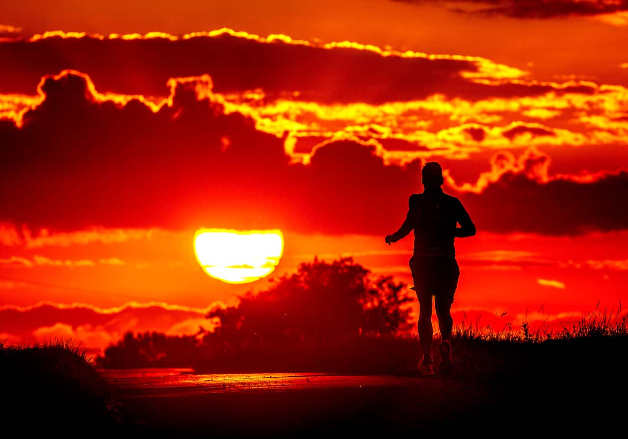A person running with the sun low in the sky in the background