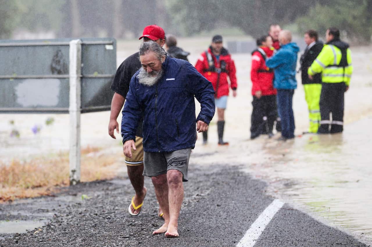 People walking along a road affected by flooding.