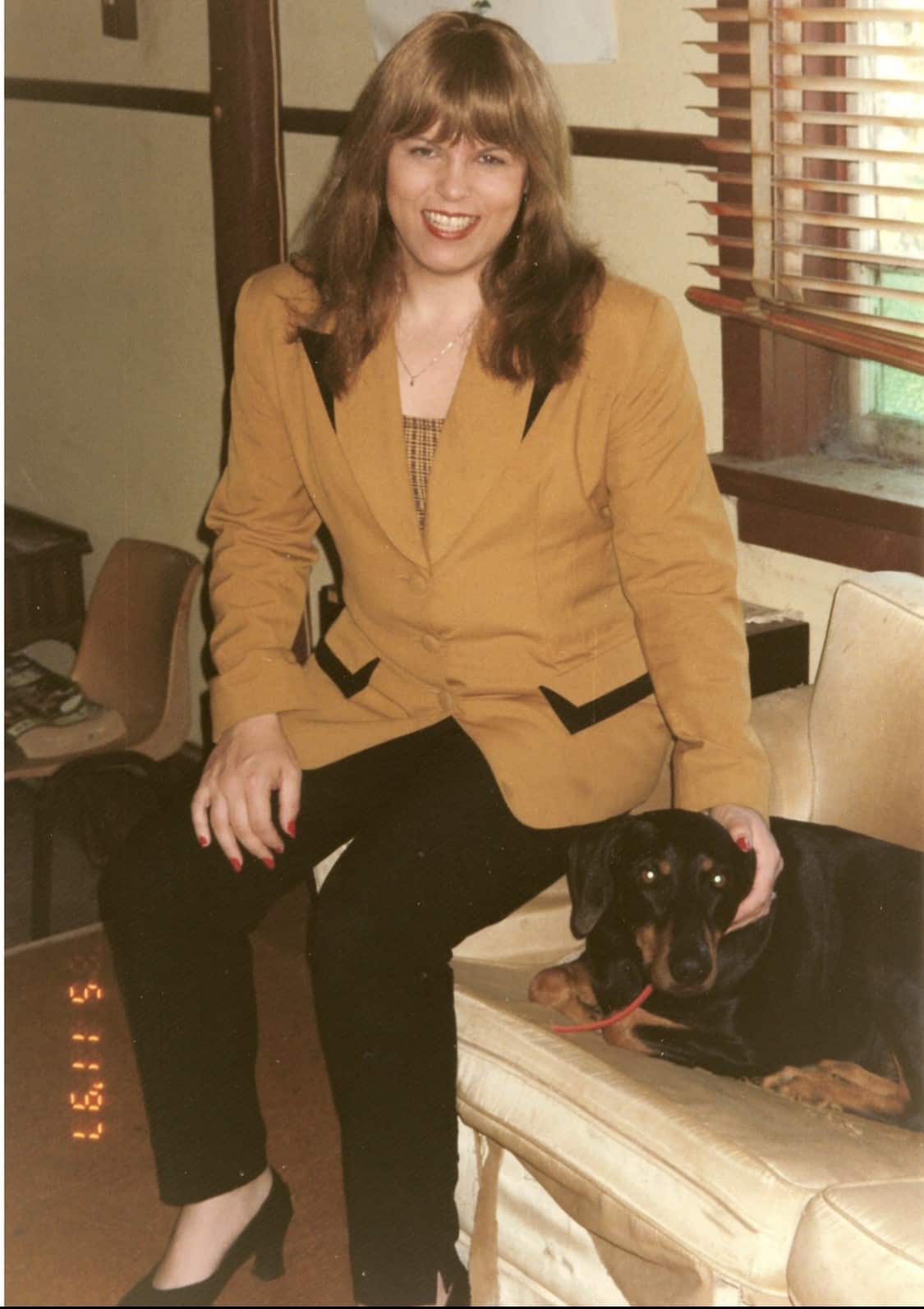 Caroline Layt sitting on a couch patting a dog.