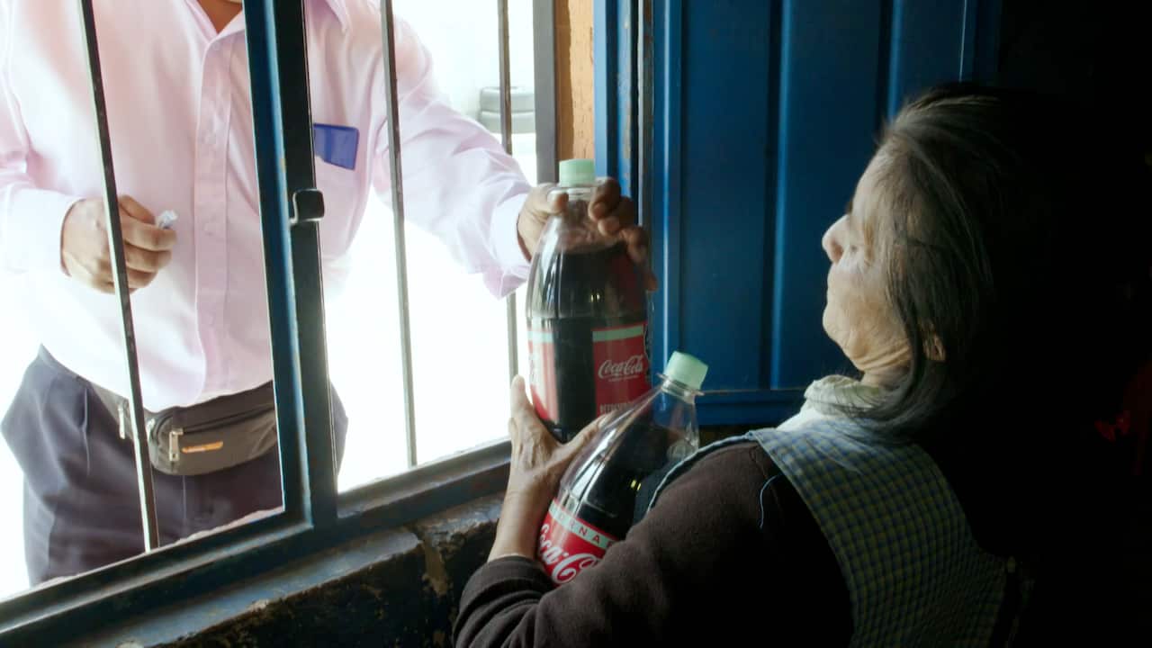 A woman sells bottles of Coca-Cola to a customer.