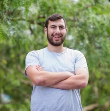 A man smiling as he crosses his arms in front of him.
