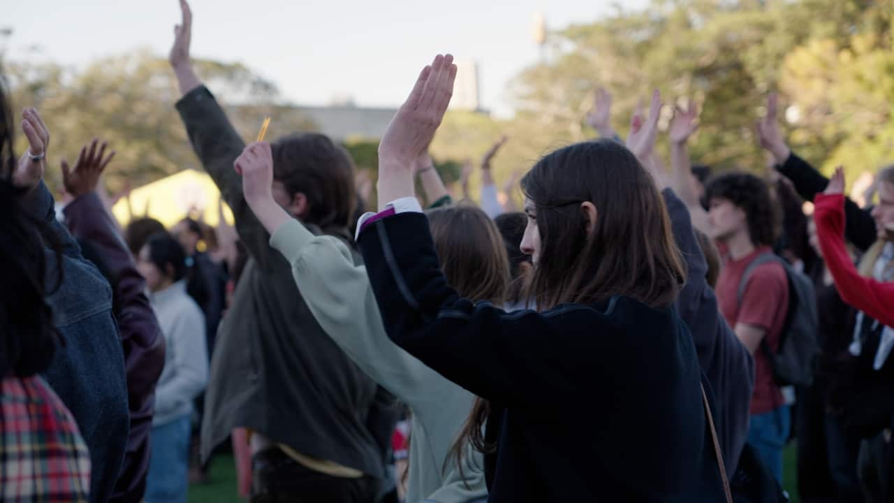 A group of young people raising their hands while standing outside