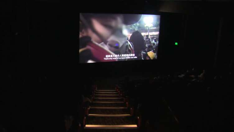 The film screen inside a movie theatre with the audience watching on.