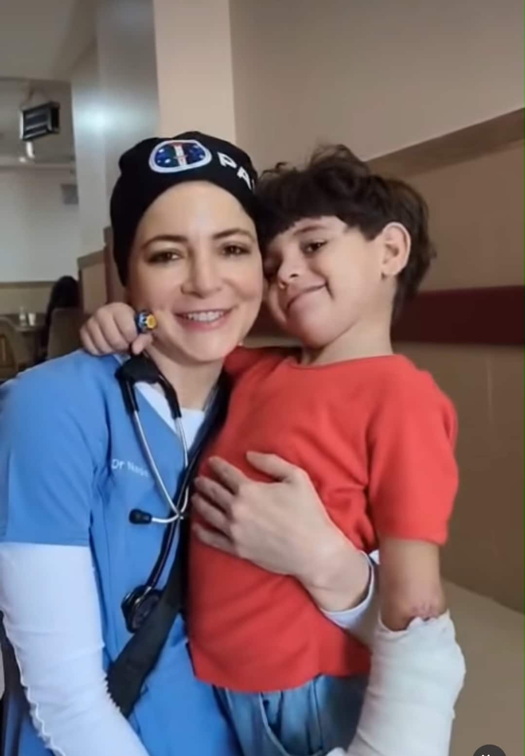 A doctor in scrubs holding a smiling child.
