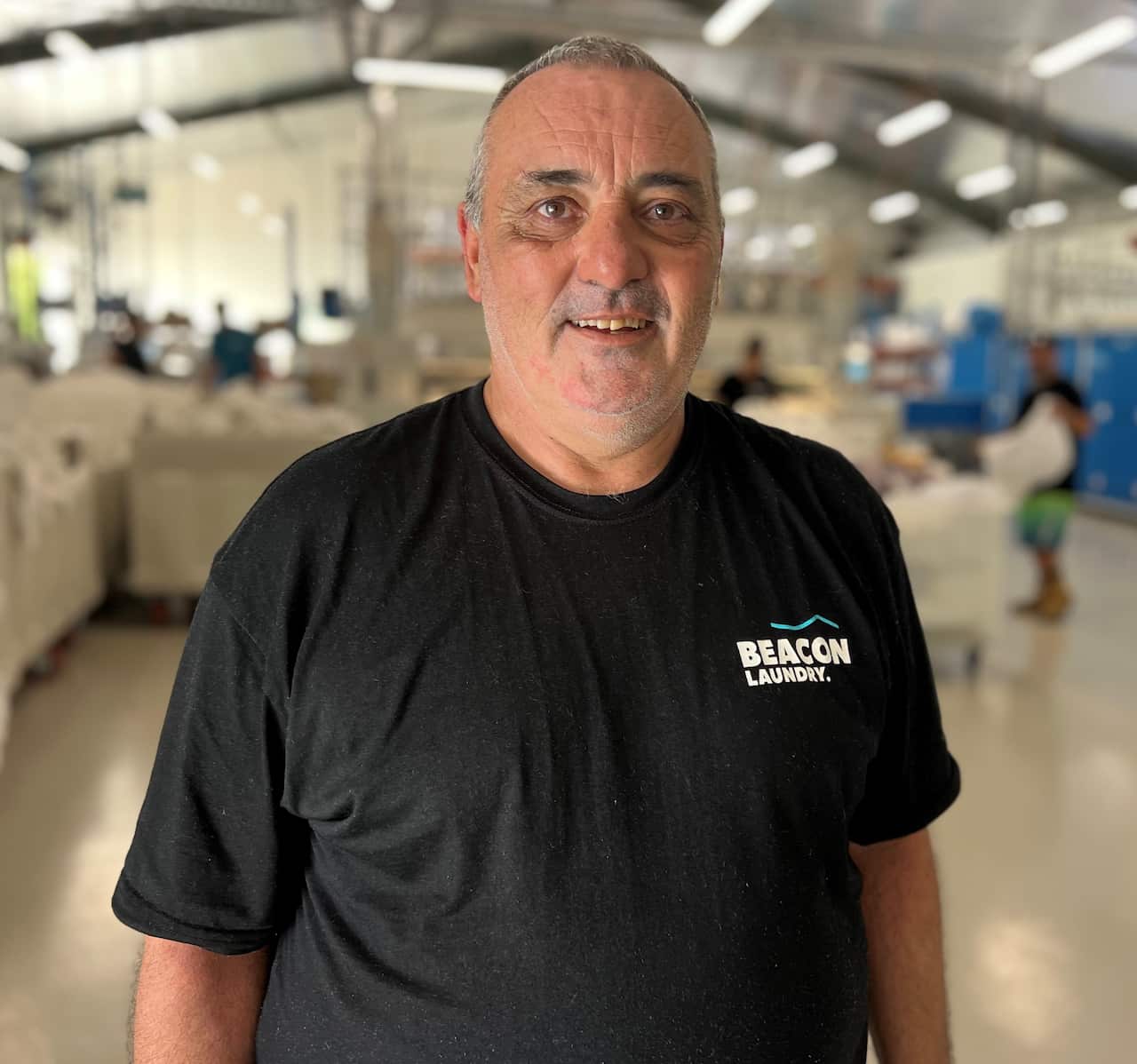 A man in a black t-shirt standing inside a warehouse.
