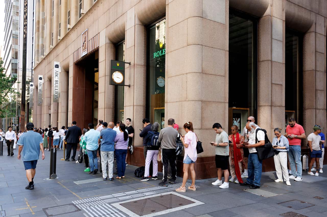 A queue of people snaking around the corner of a building.